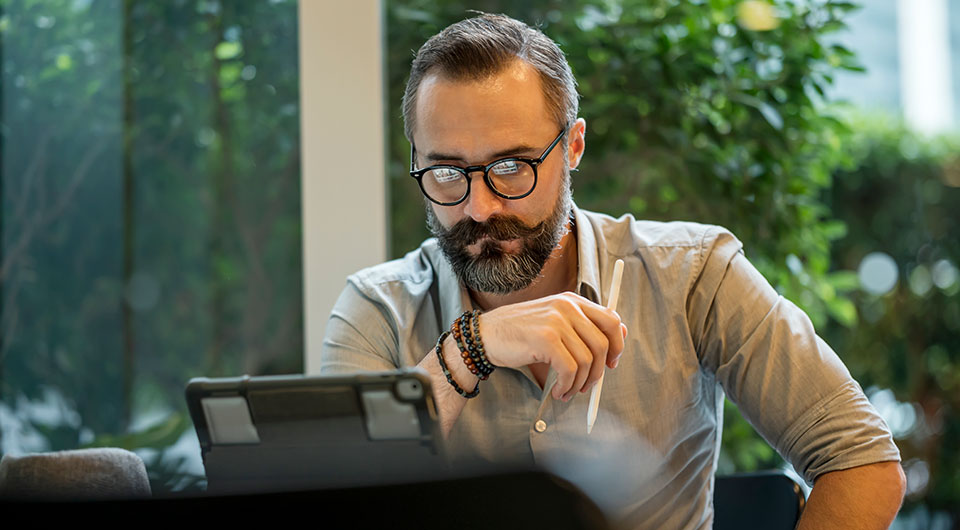 person looking contemplatively at iPad with Apple Pencil in hand