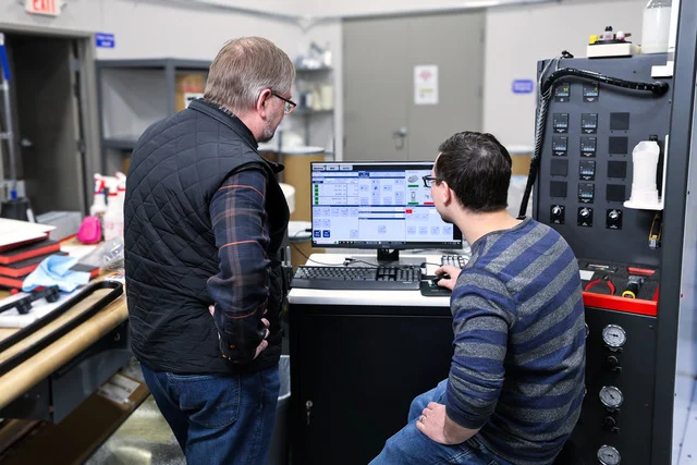 5Q9A2062-2-Edit Two Interfacial engineers reviewing data at a materials testing station